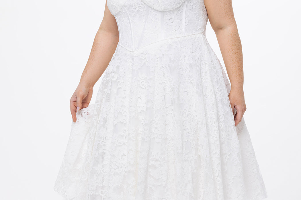 Celebrations by Sydney's Closet Style CE2613 in white. 

Plus size strapless white tea-length dress with sweetheart neckline, exposed corset boning on bustier bodice and tea-length skirt in all over stretch lace. 