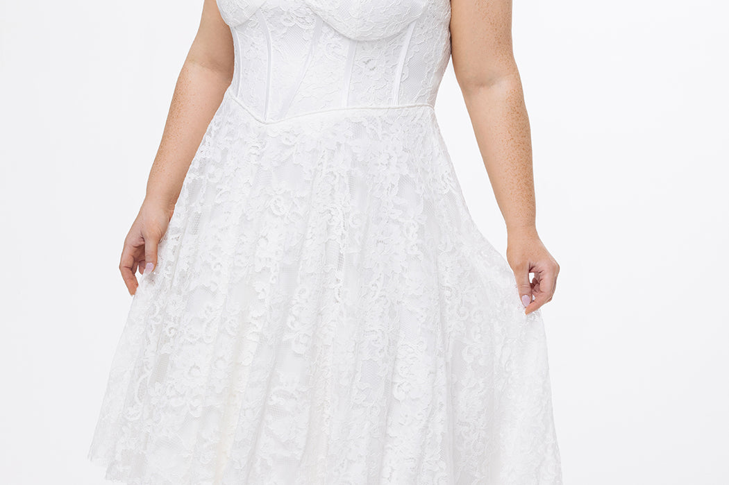 Celebrations by Sydney's Closet Style CE2613 in white. 

Plus size strapless white tea-length dress with sweetheart neckline, exposed corset boning on bustier bodice and tea-length skirt in all over stretch lace. 