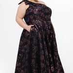Celebrations by Sydney's Closet Style CE2614 in Pink Rose and Black floral brocade fabric.

Plus size maxi length formal dress. One-shoulder neckline with detachable bow at high point of shoulder, natural waistline and A-line skirt with pockets. 