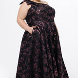 Celebrations by Sydney's Closet Style CE2614 in Pink Rose and Black floral brocade fabric.

Plus size maxi length formal dress. One-shoulder neckline with detachable bow at high point of shoulder, natural waistline and A-line skirt with pockets. 