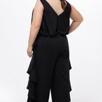 Celebrations by Sydney's Closet Style CE2615 in Black.

One-piece crepe satin jumpsuit with ruffled on outer pants seams. Bra-friendly straps, blouson bodice and wide leg pants. Center back zipper and scoop neckline. 