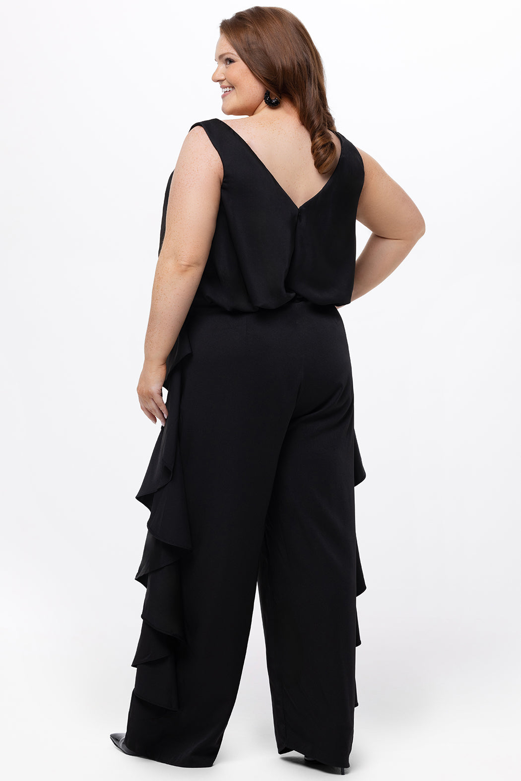 Celebrations by Sydney's Closet Style CE2615 in Black.

One-piece crepe satin jumpsuit with ruffled on outer pants seams. Bra-friendly straps, blouson bodice and wide leg pants. Center back zipper and scoop neckline. 