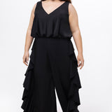 Celebrations by Sydney's Closet Style CE2615 in Black.

One-piece crepe satin jumpsuit with ruffled on outer pants seams. Bra-friendly straps, blouson bodice and wide leg pants. Center back zipper and scoop neckline. 
