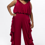 Celebrations by Sydney's Closet Style CE2615 in cherry red.

One-piece crepe satin jumpsuit with ruffled on outer pants seams. Bra-friendly straps, blouson bodice and wide leg pants. Center back zipper and scoop neckline. 