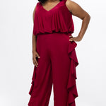 Celebrations by Sydney's Closet Style CE2615 in cherry red.

One-piece crepe satin jumpsuit with ruffled on outer pants seams. Bra-friendly straps, blouson bodice and wide leg pants. Center back zipper and scoop neckline. 