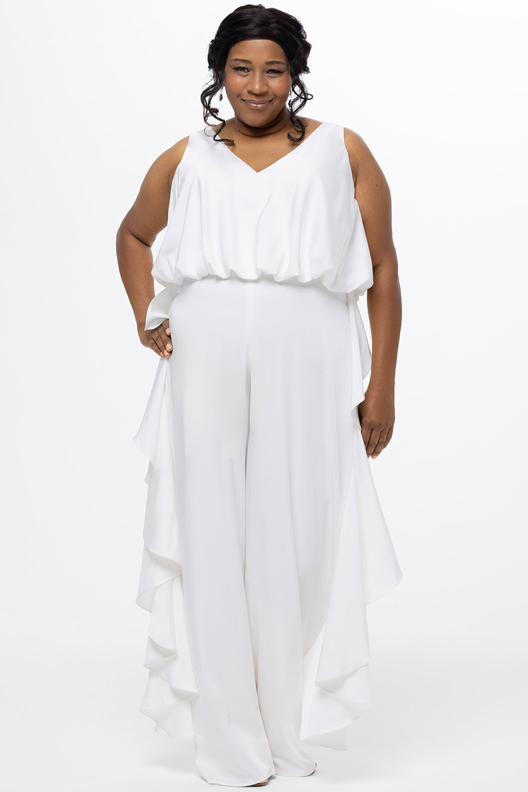 Celebration's by Sydney's Closet style CE2615 in Ivory. 

Crepe satin jumpsuit with a V-neck, bra-friendly straps, wide leg pants and blouson bodice. Ruffle detail on outer seams of pants. V-back with long center back zipper. 