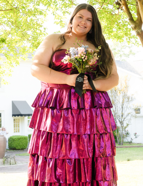 Woman in a pink strapless dress holding flowers outdoors