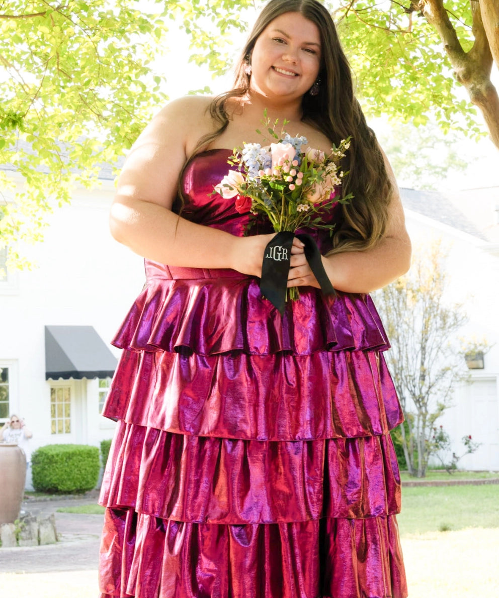 Woman in a pink strapless dress holding flowers outdoors