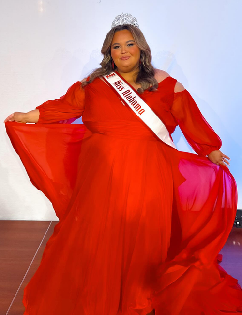 Woman in a red gown with a sash reading "Miss Alabama" and tiara, posing on a stage.