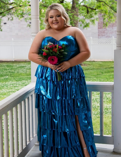 Woman in a blue strapless gown holding flowers on a porch