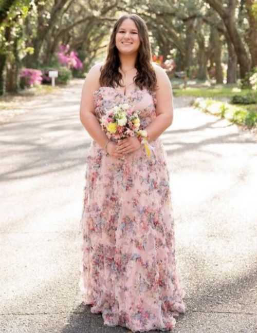 Woman in a floral dress holding flowers in a park setting