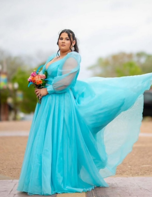 Woman in a turquoise dress holding flowers outdoors