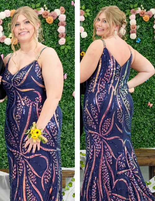 Woman in a patterned dress posing in front of a floral and greenery backdrop