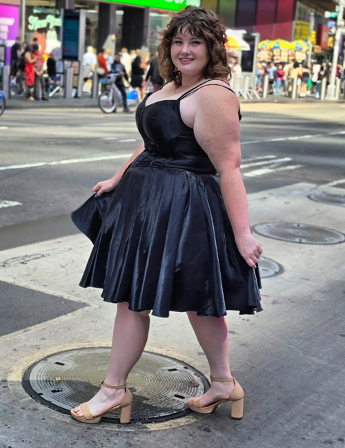 Woman in a black dress standing on a city street