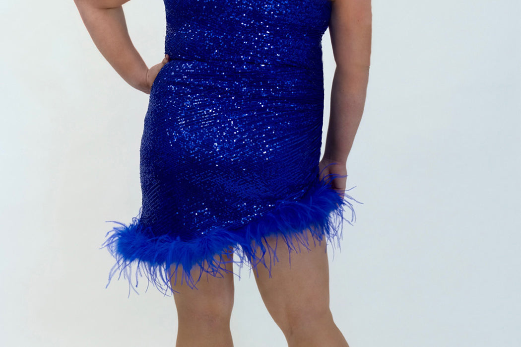 This is JK2401 in our collection Johnathan Kayne for Sydney's Closet. This plus size party dress comes in blue, red, black and white. This dress is one shoulder, all over sequins, an asymmetrical skirt, and has a feather hem.