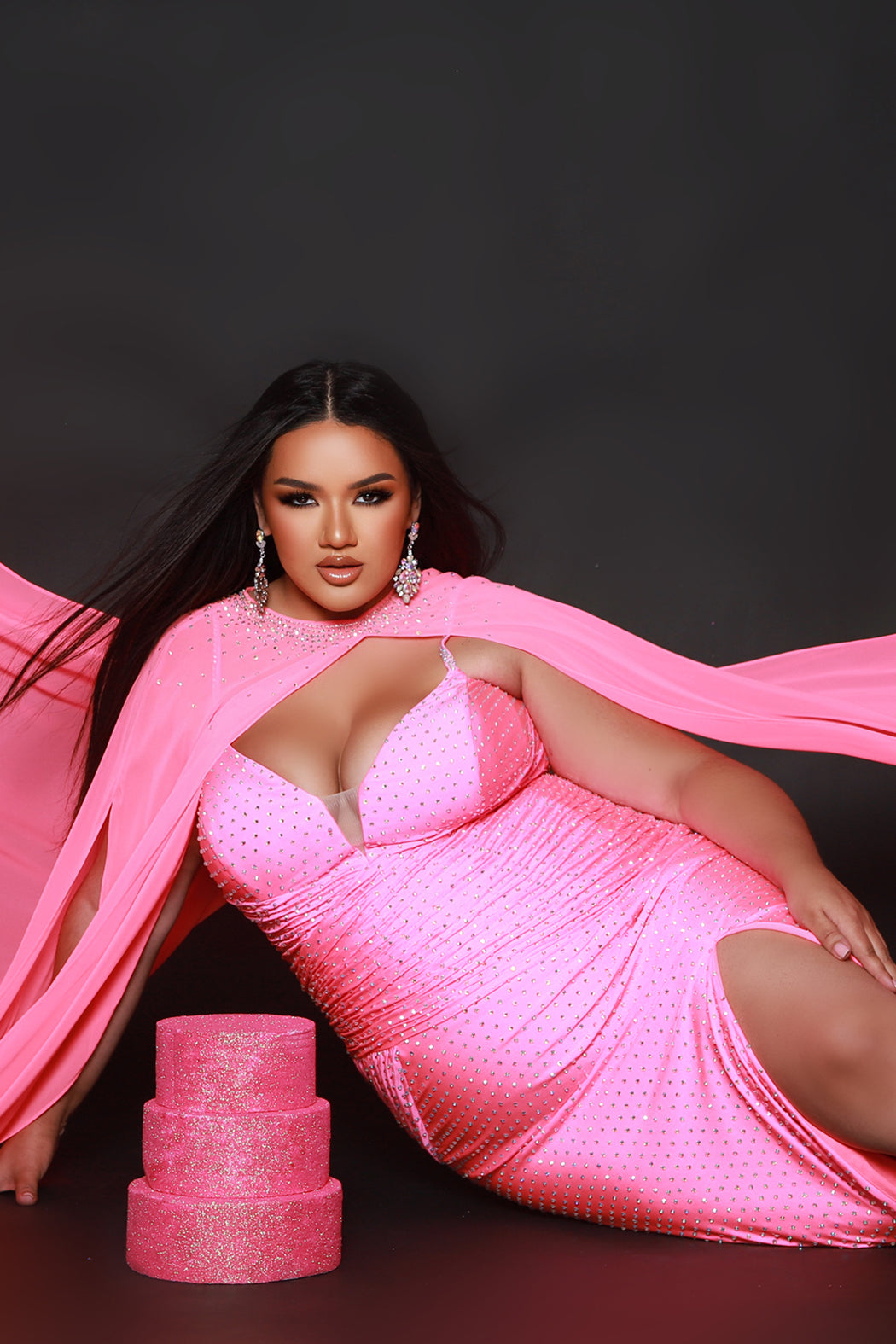 Plus size sexy fitted pageant or prom dress with detachable chiffon cape and hot fix stones.  Deep v-neckline, ruched bodice and slim fitted skirt with high slit.  Style JK2518 available in spice, ocean or hot pink from Johantahn Kayne for Sydney's Closet