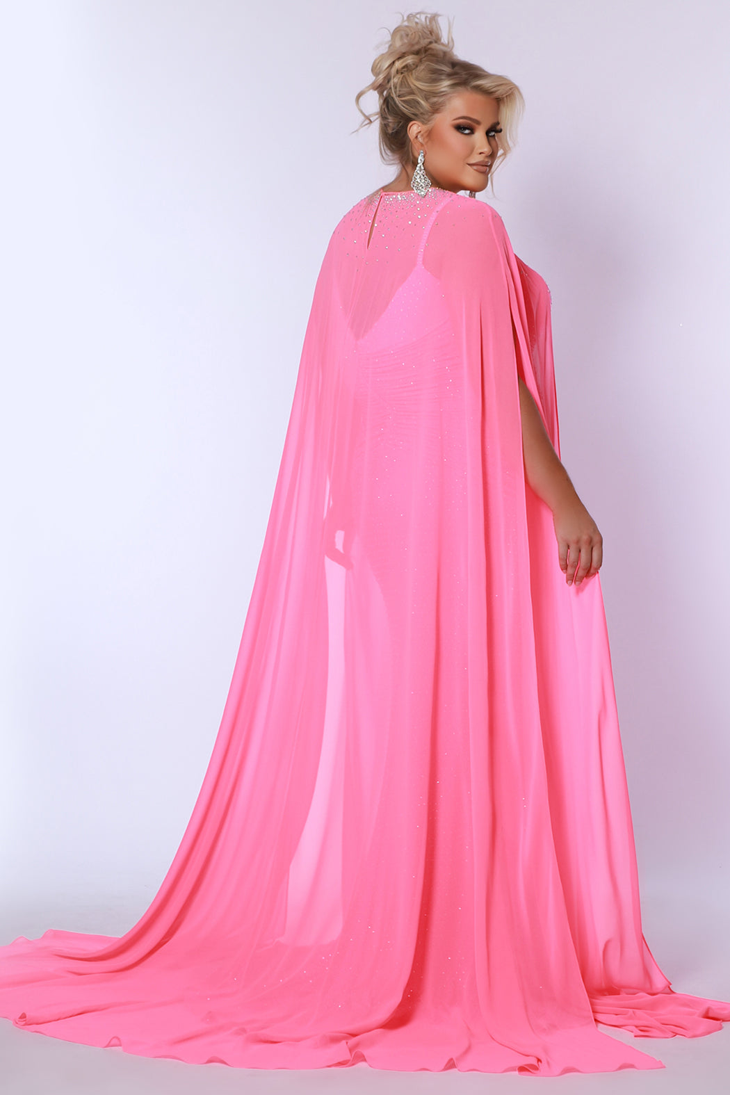 Plus size sexy fitted pageant or prom dress with detachable chiffon cape and hot fix stones.  Deep v-neckline, ruched bodice and slim fitted skirt with high slit.  Style JK2518 available in spice, ocean or hot pink from Johantahn Kayne for Sydney's Closet