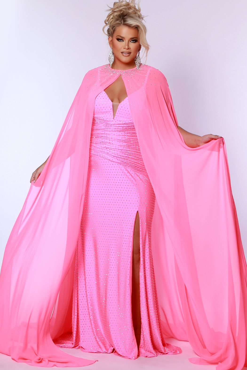 Plus size sexy fitted pageant or prom dress with detachable chiffon cape and hot fix stones.  Deep v-neckline, ruched bodice and slim fitted skirt with high slit.  Style JK2518 available in spice, ocean or hot pink from Johantahn Kayne for Sydney's Closet