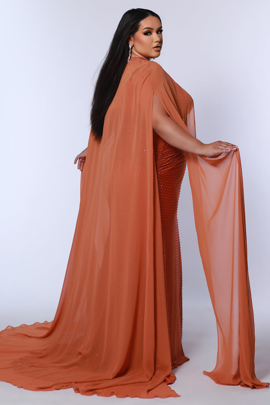 Plus size sexy fitted pageant or prom dress with detachable chiffon cape and hot fix stones.  Deep v-neckline, ruched bodice and slim fitted skirt with high slit.  Style JK2518 available in spice, ocean or hot pink from Johantahn Kayne for Sydney's Closet