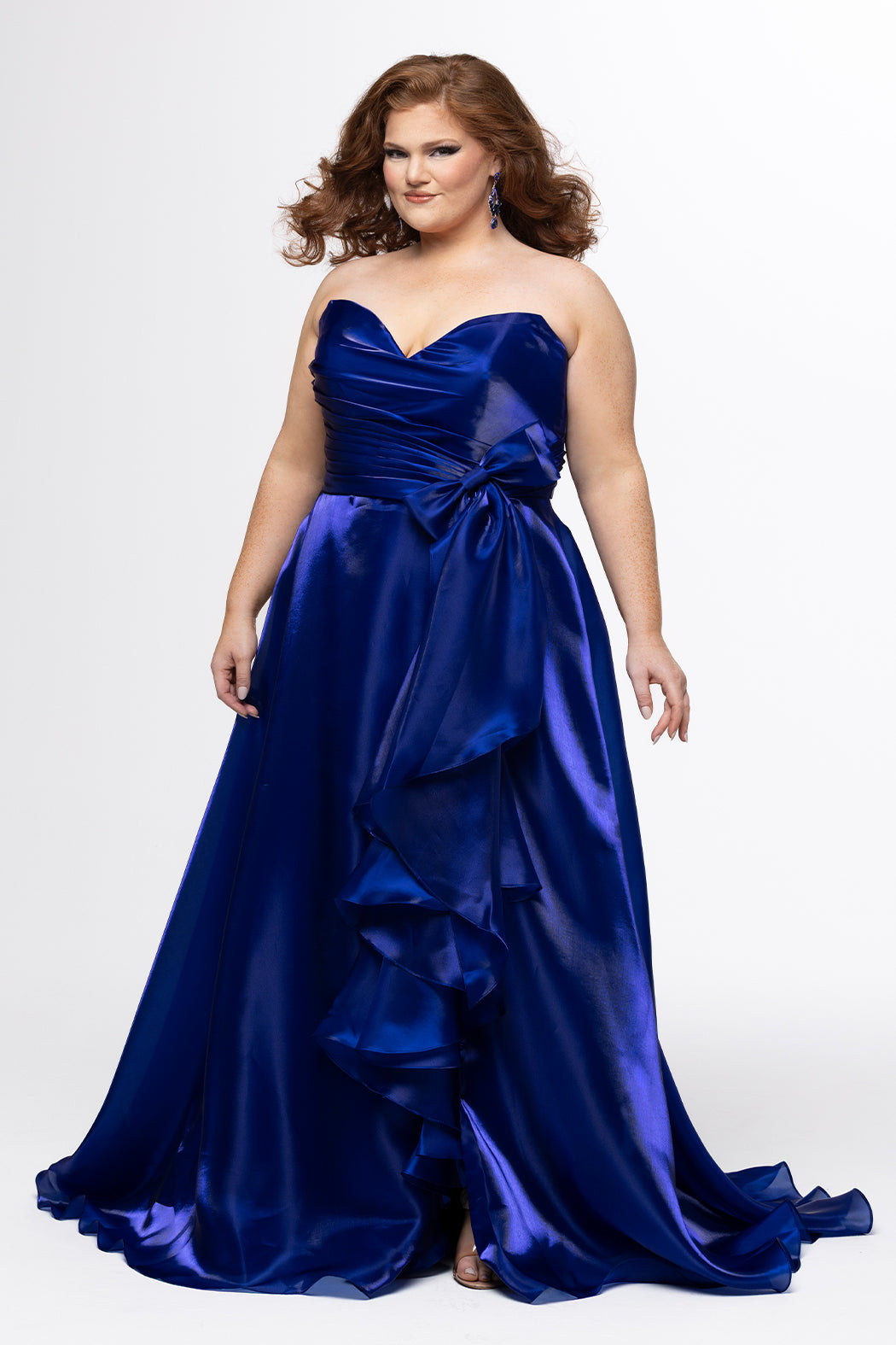 Johnathan Kayne for Sydney's Closet style JK2608.

Strapless sweetheart plus size A-line gown.  Ruched bodice with bow at natural waistline and flounce down left leg slit. Shiny organza fabric for lightweight comfort. Available in sizes  10-32 in Red, Black and Blue. 