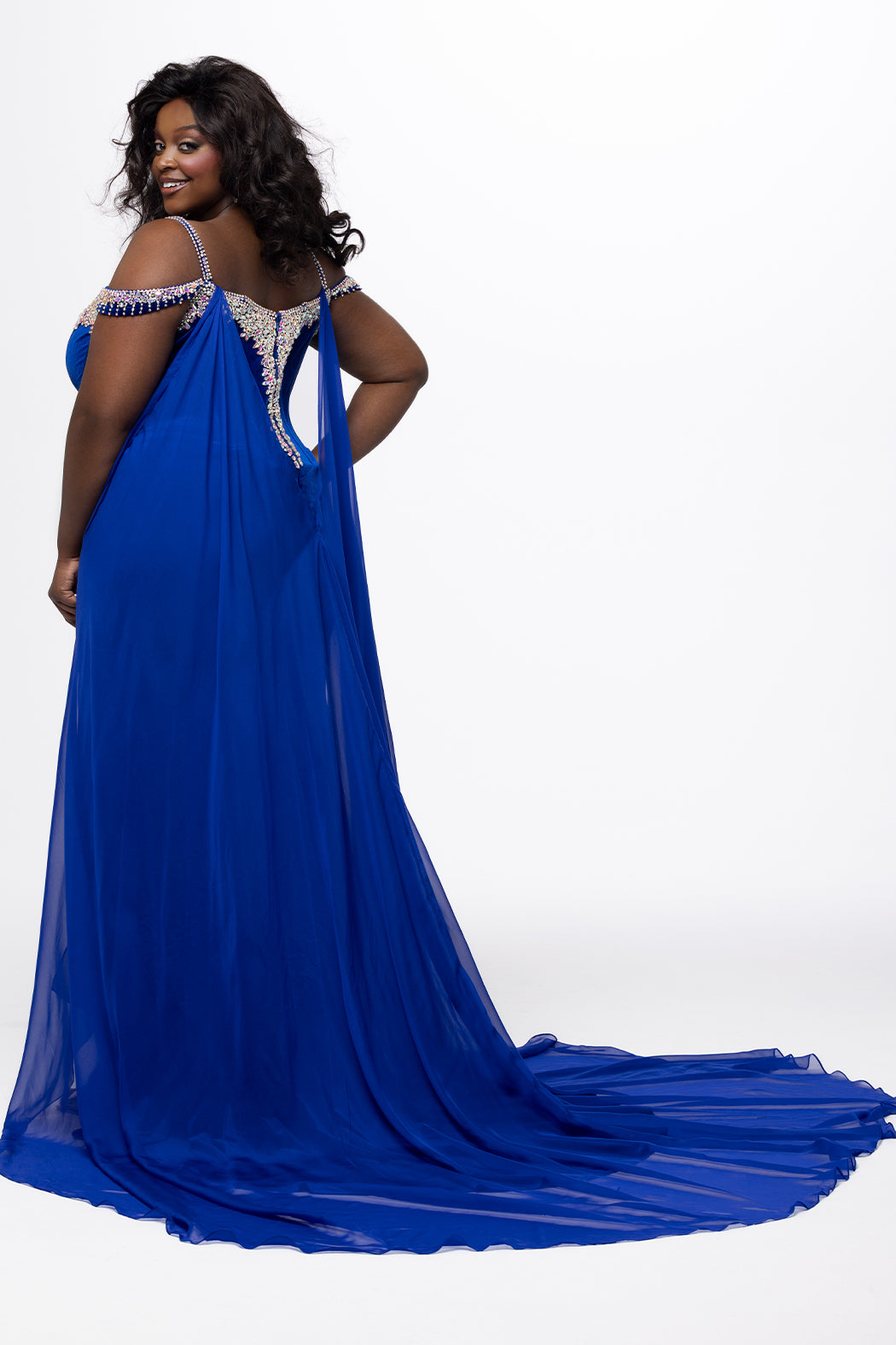 Johnathan Kayne for Sydney's Closet style JK2610.

Stretch velvet fitted plus size evening gown.  AB stoned v-neckline with stoned spaghetti straps. Off-the-shoulder stoned drapes straps, left leg slit and sweep train. Chiffon cape attached at back. Available in sizes 10-28 in black and royal blue. 
