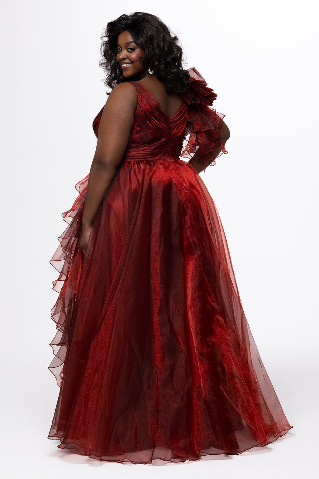 Johnathan Kayne for Sydney's Closet style JK2611. 

Plus size A-line gown made with multidimensional organza. Thick straps with detachable ruffle at shoulder. Ruched waistband with natural waistline and left leg slit with large ruffle. Deep v-neckline and center back zipper. Available in sizes 10-32 in purple and red. 