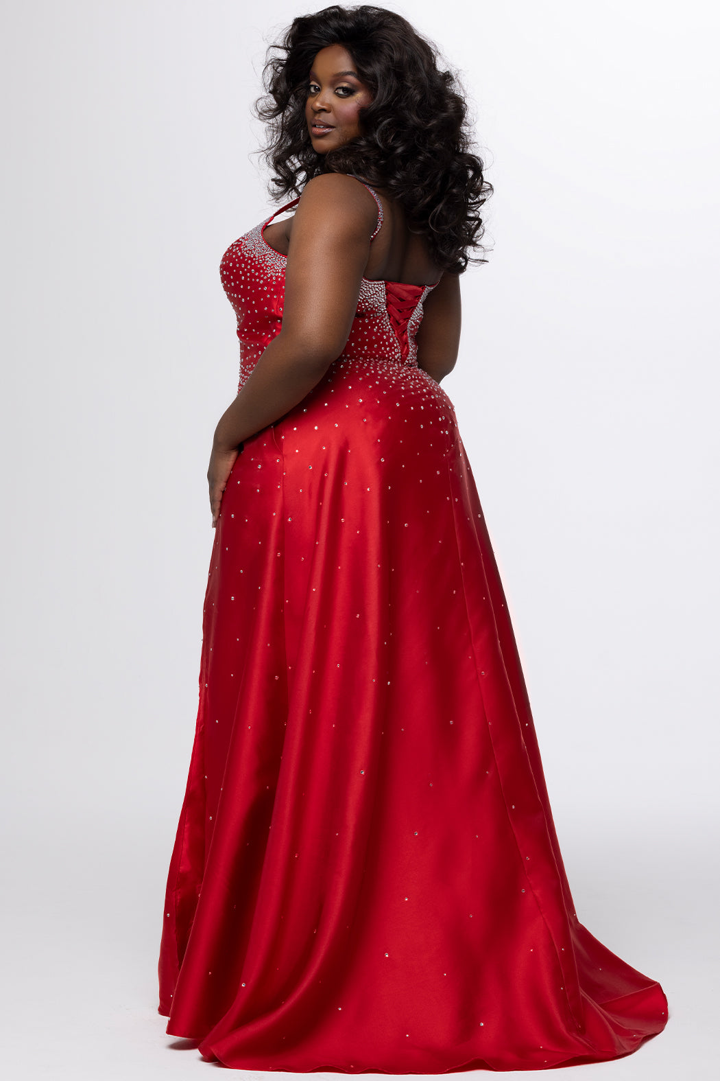 Johnathan Kayne for Sydney's Closet style JK2613. 

Plus size A-line gown with hot fix stones on thick satin fabric. Heavily embellished deep V-neckline with nude-mesh insert and embellished one inch straps. A-line skirt with left leg slit. Lace up back with modesty panel and half zipper. Available in sizes 10-32 in red, blue and black. 