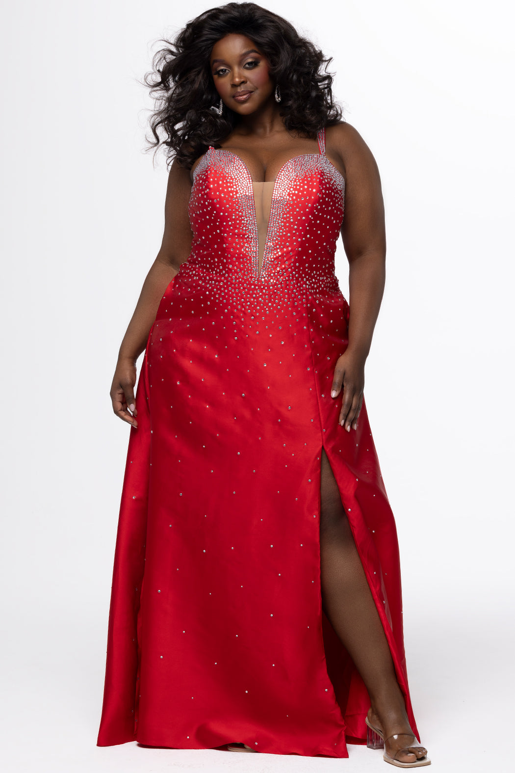 Johnathan Kayne for Sydney's Closet style JK2613. 

Plus size A-line gown with hot fix stones on thick satin fabric. Heavily embellished deep V-neckline with nude-mesh insert and embellished one inch straps. A-line skirt with left leg slit. Lace up back with modesty panel and half zipper. Available in sizes 10-32 in red, blue and black. 