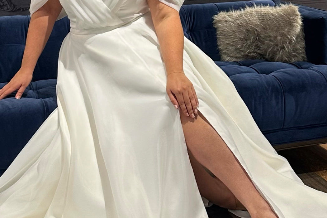 Michelle Bridal MB2506 plus size wedding dress by Sydney's Closet. Off-the-shoulder pleated straps, organza ballgown with slit and long train available in black, ivory or mauve pink