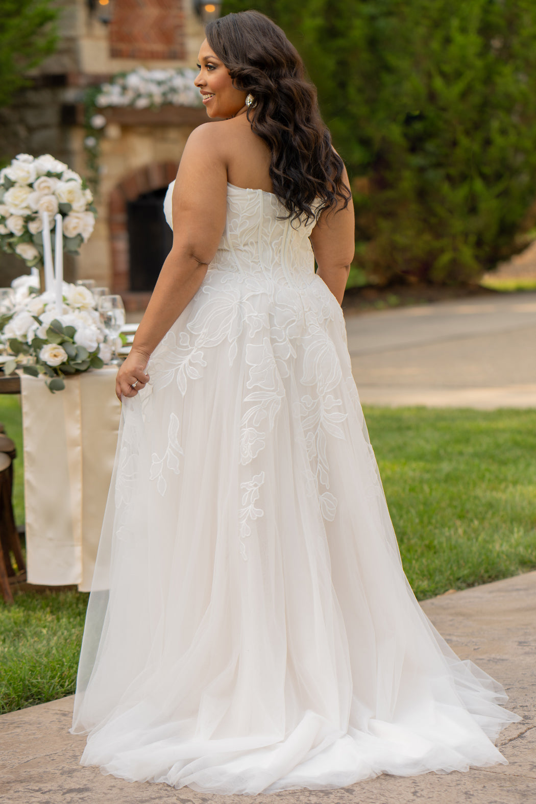 Michelle Bridal MB2605. Strapless A-line gown with bodice drape detail, exposed boning, basque waistline and soft tulle A-Line skirt. Large embroidered organza appliques. Center back zipper. 