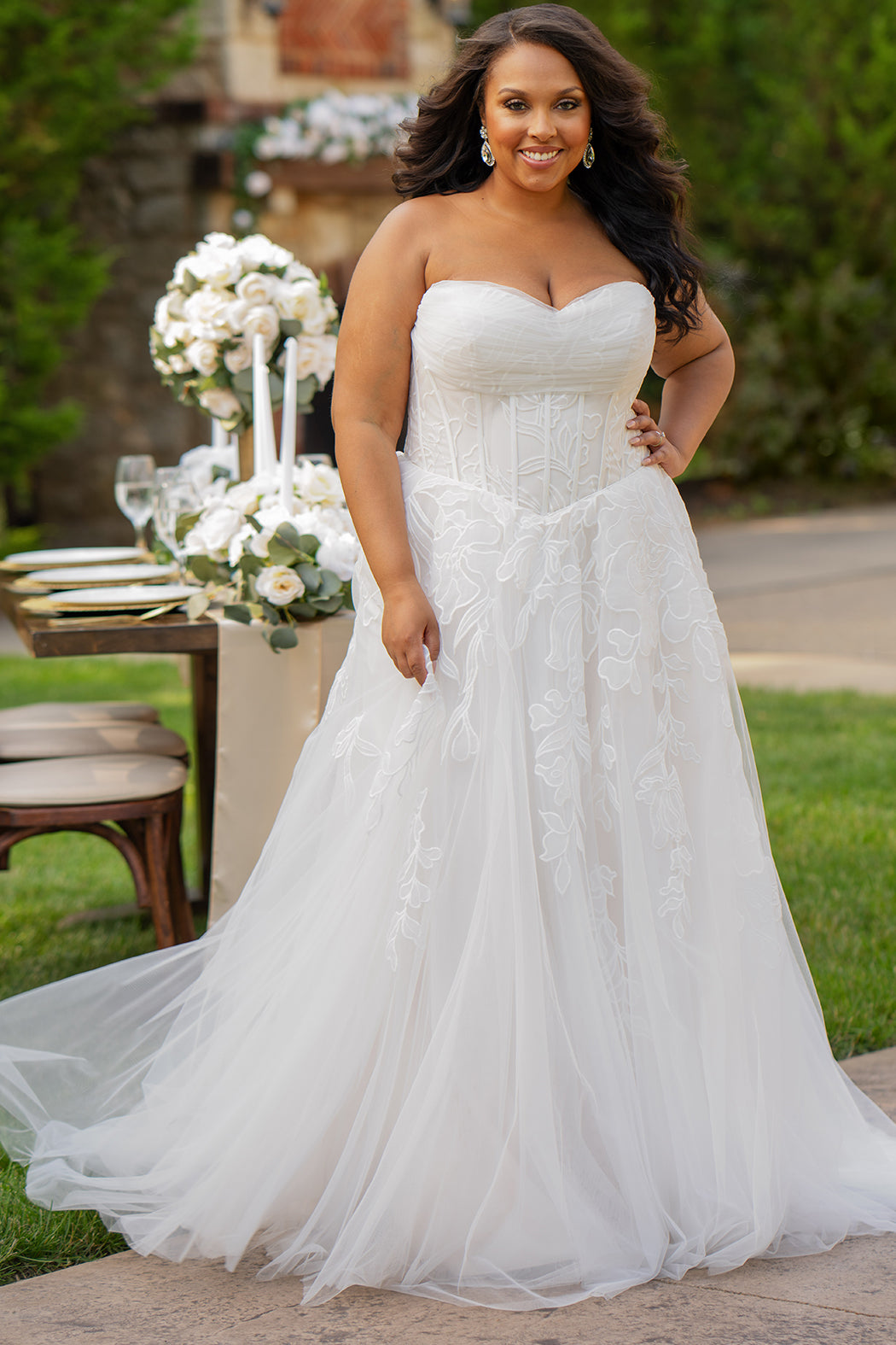 Michelle Bridal MB2605. Strapless A-line gown with bodice drape detail, exposed boning, basque waistline and soft tulle A-Line skirt. Large embroidered organza appliques. Center back zipper. 