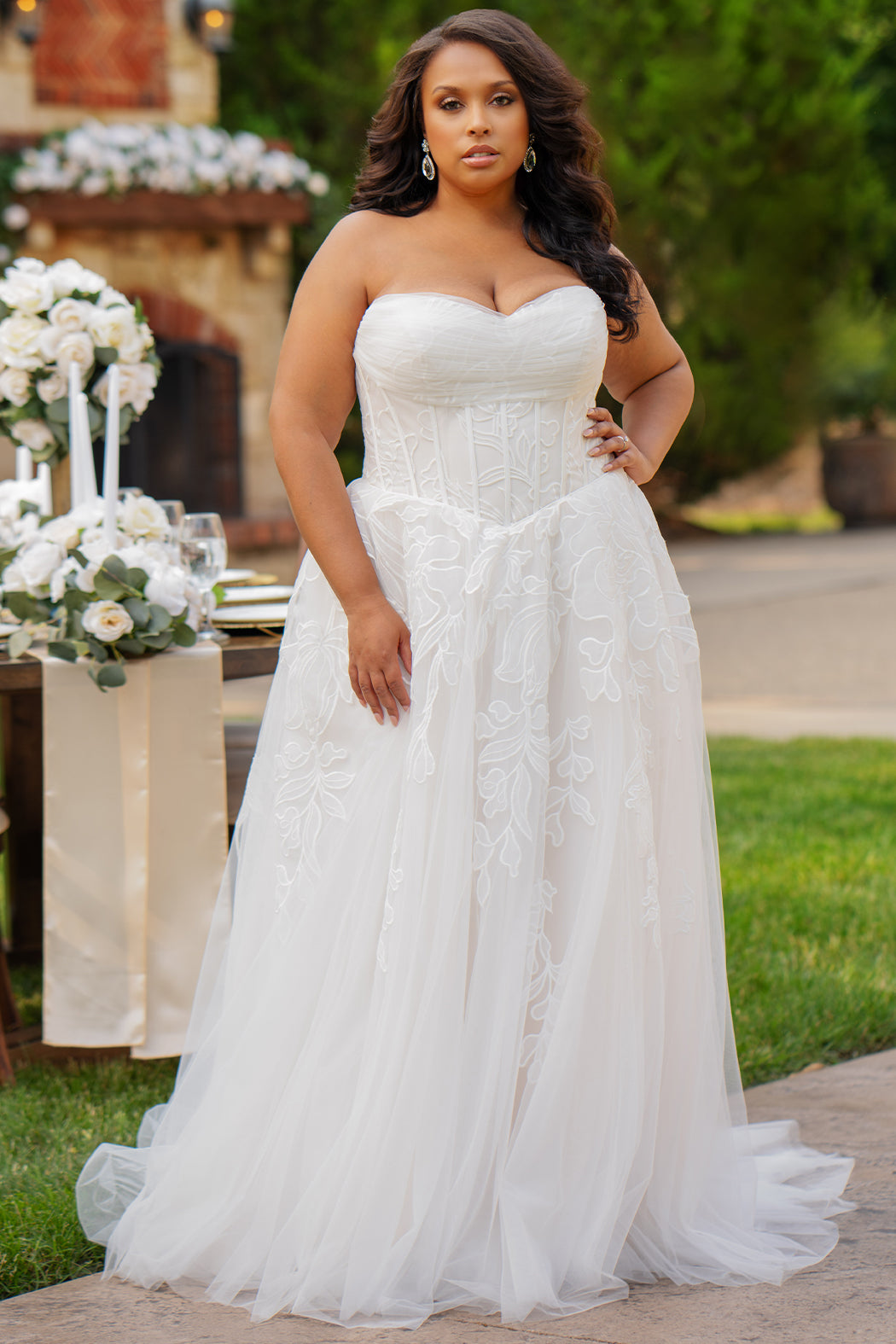 Michelle Bridal MB2605. Strapless A-line gown with bodice drape detail, exposed boning, basque waistline and soft tulle A-Line skirt. Large embroidered organza appliques. Center back zipper. 