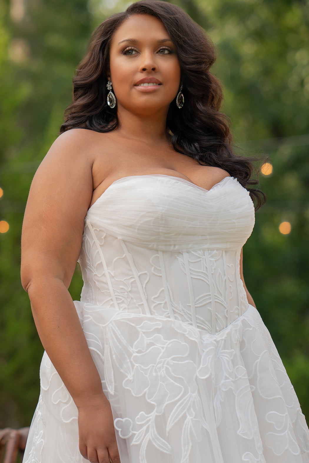 Michelle Bridal MB2605. Strapless A-line gown with bodice drape detail, exposed boning, basque waistline and soft tulle A-Line skirt. Large embroidered organza appliques. Center back zipper. 