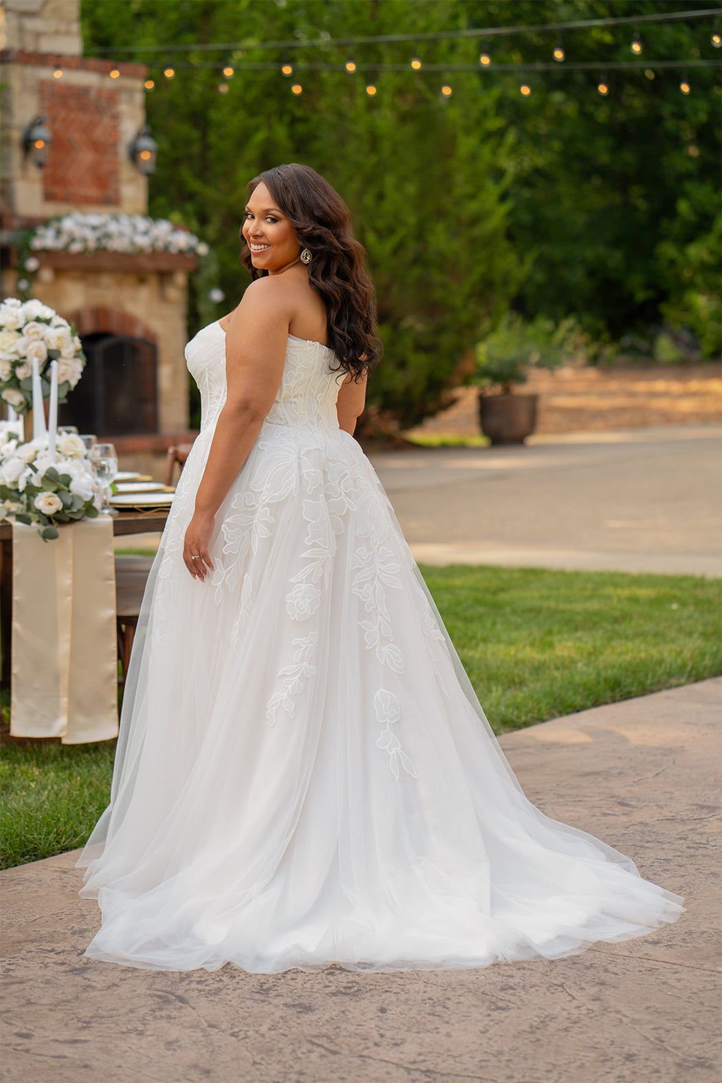 Michelle Bridal MB2605. Strapless A-line gown with bodice drape detail, exposed boning, basque waistline and soft tulle A-Line skirt. Large embroidered organza appliques. Center back zipper. 