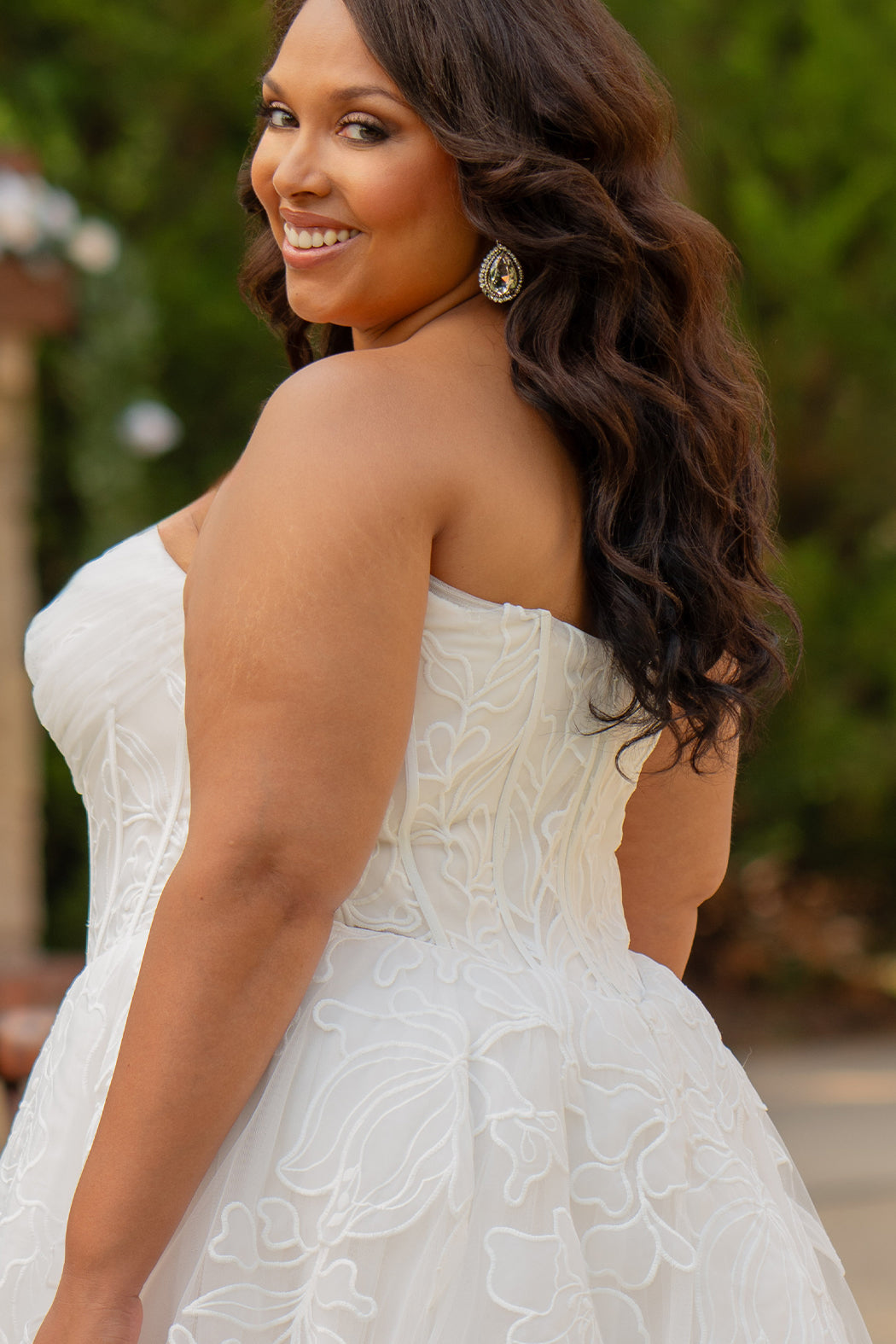 Michelle Bridal MB2605. Strapless A-line gown with bodice drape detail, exposed boning, basque waistline and soft tulle A-Line skirt. Large embroidered organza appliques. Center back zipper. 