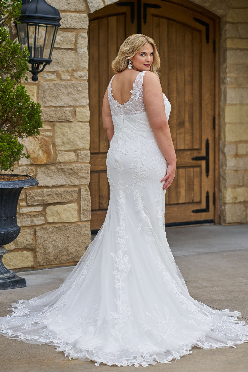 Michelle Bridal MB2606 in ivory. Fitted gown with bra-friendly straps, natural waistline, v-neckline, scoop lace back and center back zipper. Black Soft tulle, floral organza appliques over a champagne stretch knit lining. Train.