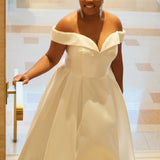 Michelle Bridal MB2610 shown in ivory. Off-the-shoulder satin A-line gown, bodice cuff covered in pearls and clear beads. Natural waistline, box pleats on skirt and center back zipper. Long satin train. 