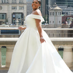 Michelle Bridal MB2610 shown in ivory. Off-the-shoulder satin A-line gown, bodice cuff covered in pearls and clear beads. Natural waistline, box pleats on skirt and center back zipper. Long satin train. 