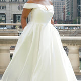 Michelle Bridal MB2610 shown in ivory. Off-the-shoulder satin A-line gown, bodice cuff covered in pearls and clear beads. Natural waistline, box pleats on skirt and center back zipper. Long satin train. 