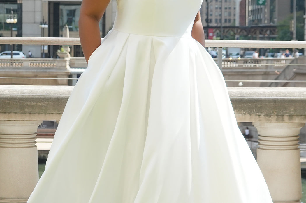 Michelle Bridal MB2610 shown in ivory. Off-the-shoulder satin A-line gown, bodice cuff covered in pearls and clear beads. Natural waistline, box pleats on skirt and center back zipper. Long satin train. 