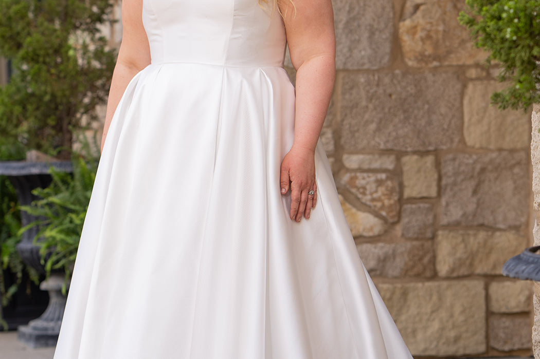 Michelle Bridal MB2610 shown in ivory. Off-the-shoulder satin A-line gown, bodice cuff covered in pearls and clear beads. Natural waistline, box pleats on skirt and center back zipper. Long satin train. 