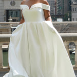 Michelle Bridal MB2610 shown in ivory. Off-the-shoulder satin A-line gown, bodice cuff covered in pearls and clear beads. Natural waistline, box pleats on skirt and center back zipper. Long satin train. 