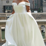 Michelle Bridal MB2610 shown in ivory. Off-the-shoulder satin A-line gown, bodice cuff covered in pearls and clear beads. Natural waistline, box pleats on skirt and center back zipper. Long satin train. 