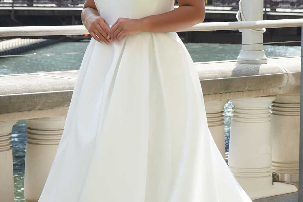 Michelle Bridal MB2610 shown in ivory. Off-the-shoulder satin A-line gown, bodice cuff covered in pearls and clear beads. Natural waistline, box pleats on skirt and center back zipper. Long satin train. 