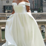 Michelle Bridal MB2610 shown in ivory. Off-the-shoulder satin A-line gown, bodice cuff covered in pearls and clear beads. Natural waistline, box pleats on skirt and center back zipper. Long satin train. 