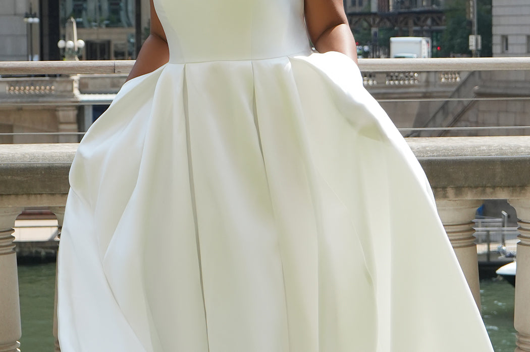 Michelle Bridal MB2610 shown in ivory. Off-the-shoulder satin A-line gown, bodice cuff covered in pearls and clear beads. Natural waistline, box pleats on skirt and center back zipper. Long satin train. 