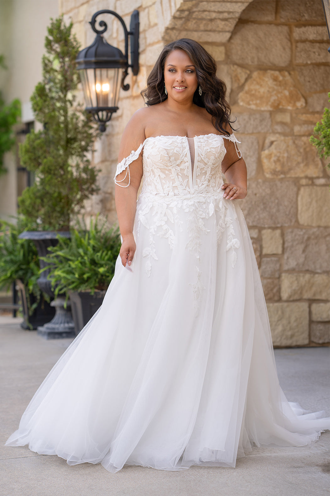 Michelle Bridal MB2611 shown in Ivory/Nude. 
Strapless bodice with deep v-neckline, exposed boning and optional drape straps with beaded detail. Soft bridal tulle A-line skirt with floral appliques, center back zipper. 