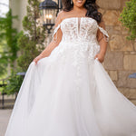 Michelle Bridal MB2611 shown in Ivory/Nude. 
Strapless bodice with deep v-neckline, exposed boning and optional drape straps with beaded detail. Soft bridal tulle A-line skirt with floral appliques, center back zipper. 