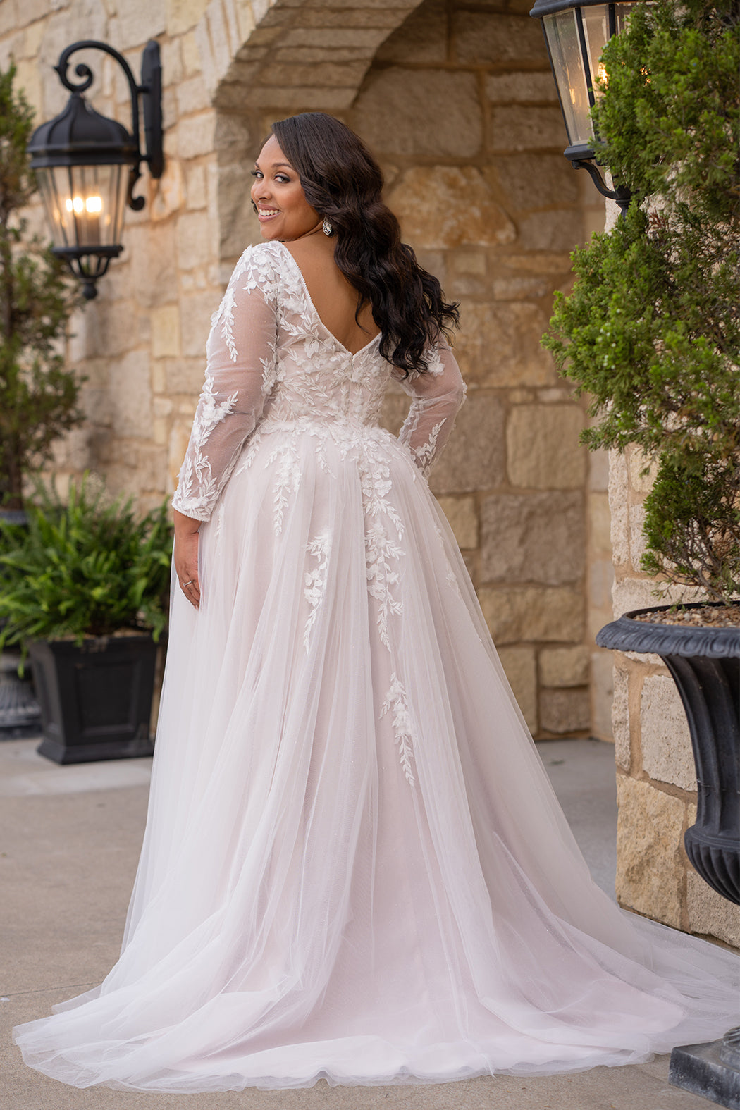 Michelle Bridal MB2612 shown in Ivory/Rosewater. 

Long sleeve tulle A-line, lace covered bodice, v-neckline and 5 inch waistband. Flowy tulle skirt with slit, satin lining and scattered lace appliques. V-back and center back zipper. 