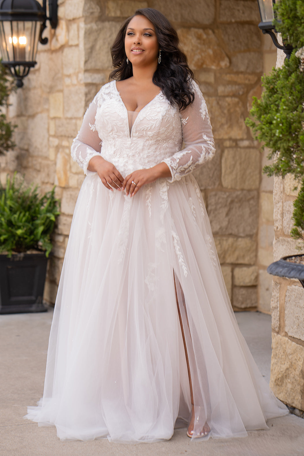 Michelle Bridal MB2612 shown in Ivory/Rosewater. 

Long sleeve tulle A-line, lace covered bodice, v-neckline and 5 inch waistband. Flowy tulle skirt with slit, satin lining and scattered lace appliques. V-back and center back zipper. 